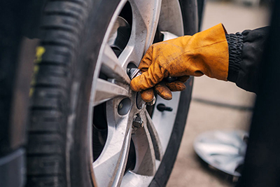 AER Towing Jumpstart Service Miami Gloved hand checking a car's tire pressure