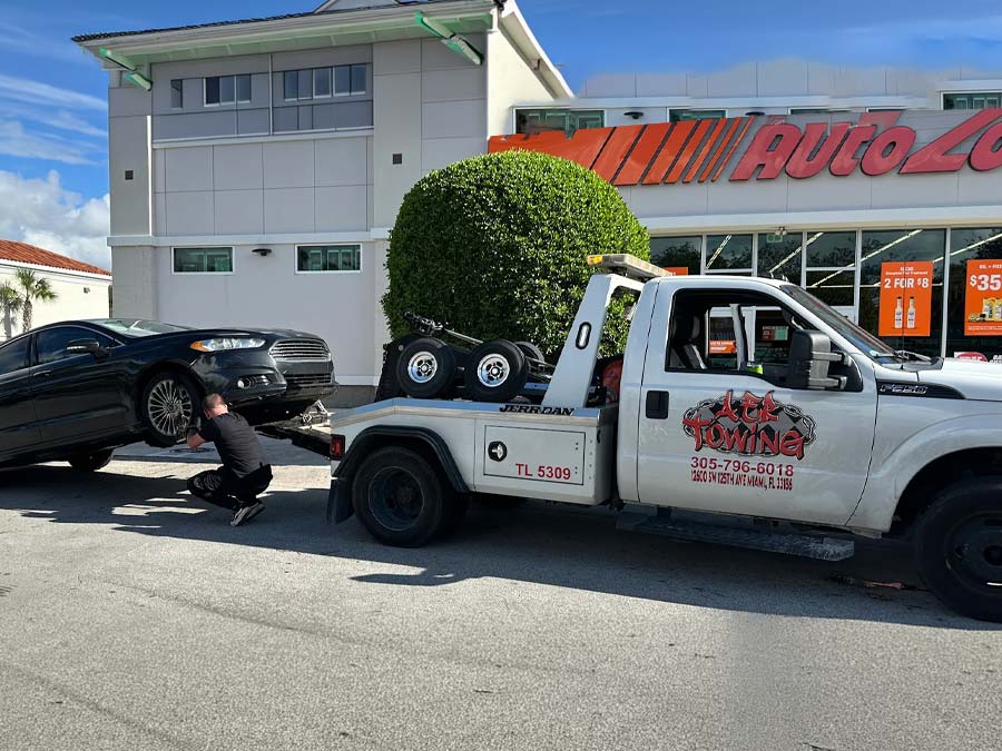 Tow Truck In Miami Hooking up a black passenger car to be towed to a repair shop