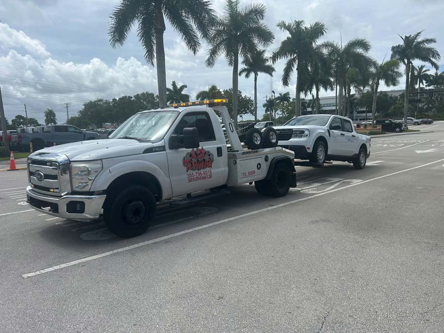 White AER Towing tow truck towing a pickup truck 